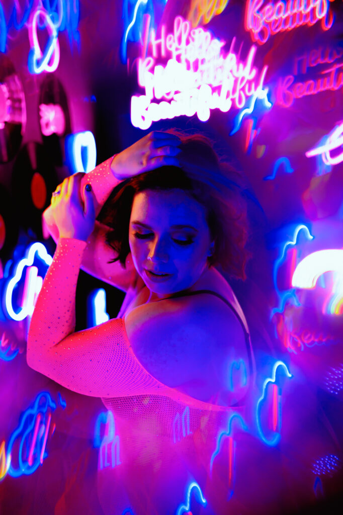 A woman in neon pink lingerie, radiating in a neon alley, surrounded by vibrant lights.