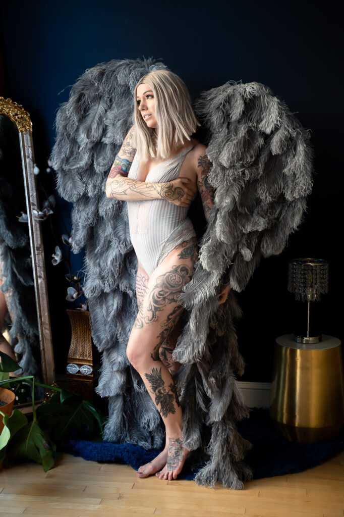 A celestial-inspired image of a woman in gray lingerie, standing gracefully with gray angel wings.